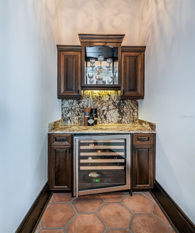 bar featuring a dry bar, beverage cooler, baseboards, and backsplash