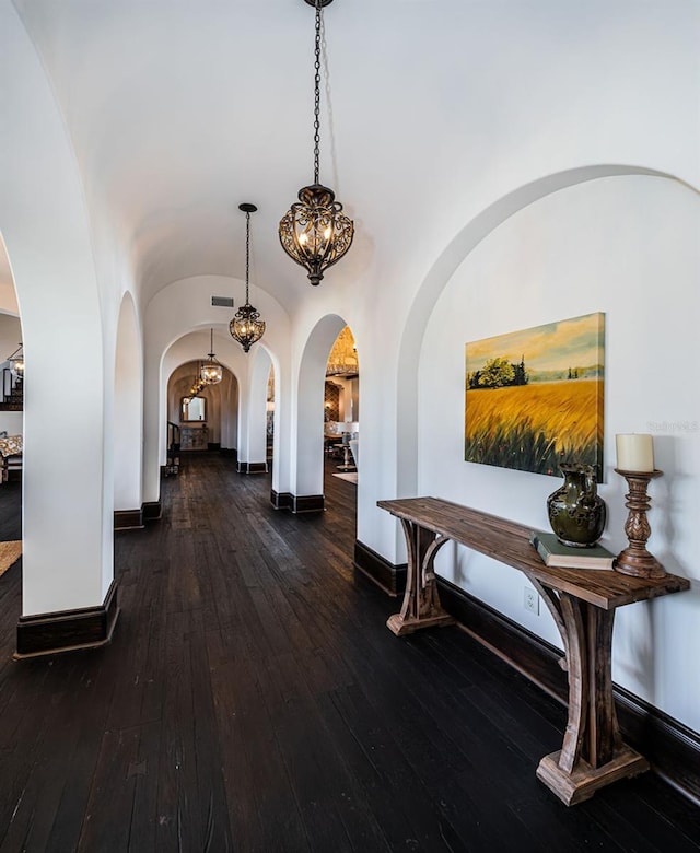 hall with lofted ceiling, visible vents, dark wood finished floors, and baseboards