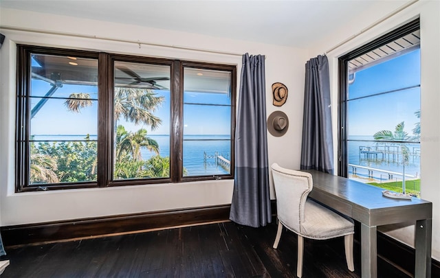 dining room with a water view, dark wood finished floors, and baseboards