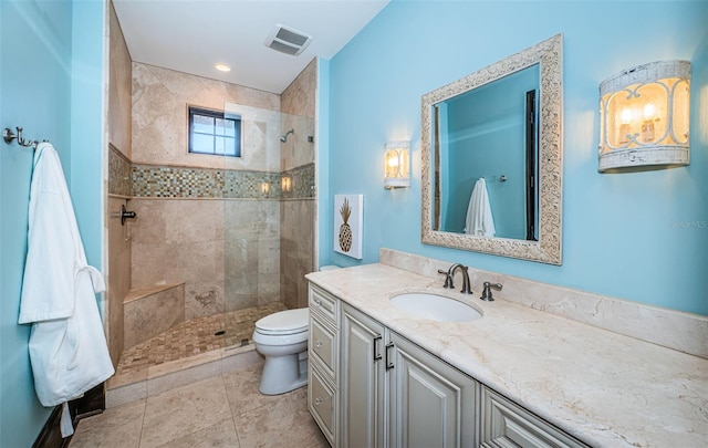 full bathroom featuring visible vents, toilet, a tile shower, vanity, and tile patterned floors