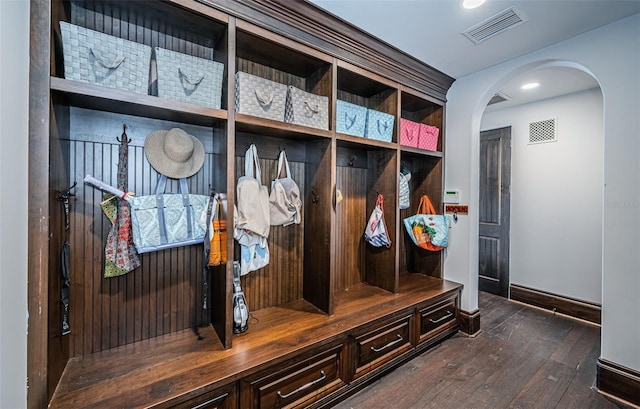 mudroom featuring arched walkways, dark wood-type flooring, visible vents, and baseboards