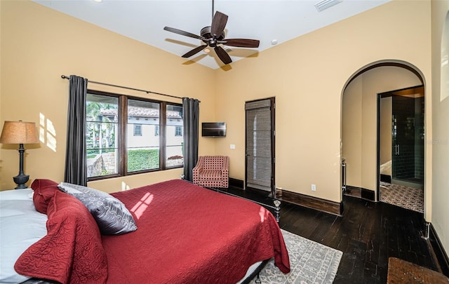 bedroom with dark wood-style floors, arched walkways, visible vents, ceiling fan, and baseboards