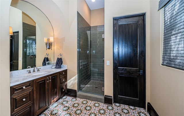 bathroom with baseboards, vanity, a shower stall, and tile patterned floors