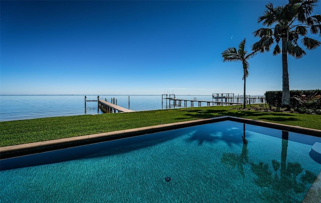 view of pool with a lawn, a water view, and a dock