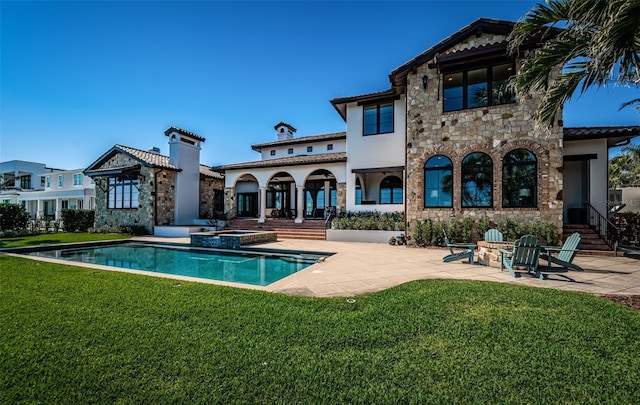 rear view of house with a patio, a pool with connected hot tub, a yard, stone siding, and stucco siding