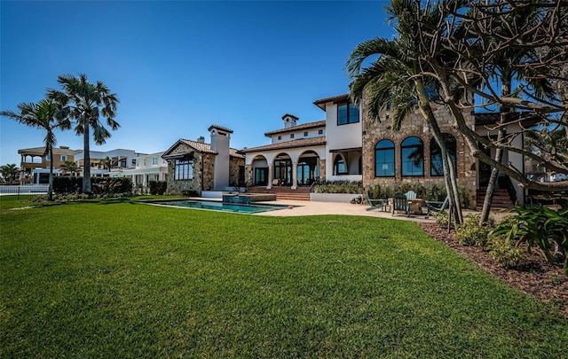 back of property featuring a patio area, stone siding, and a yard