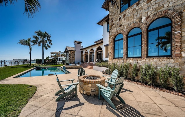 view of pool with a patio area, a pool with connected hot tub, and a fire pit