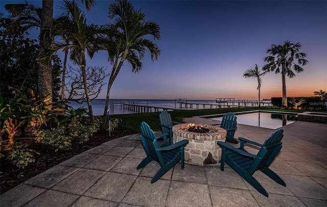 patio terrace at dusk featuring an outdoor fire pit and a water view