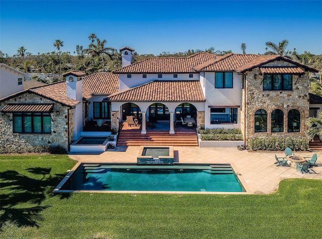 rear view of property featuring a tile roof, a yard, a patio, a chimney, and stone siding