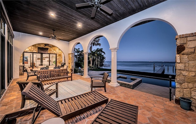 view of patio featuring a view of the beach, an outdoor living space with a fire pit, a water view, and ceiling fan