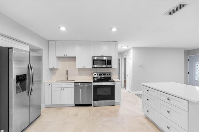 kitchen with sink, backsplash, white cabinetry, and stainless steel appliances