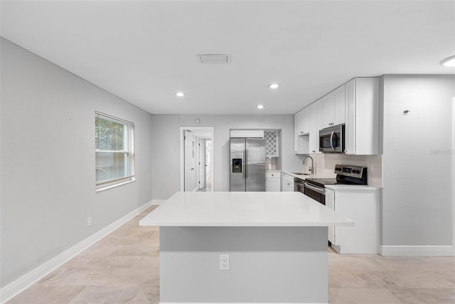 kitchen featuring appliances with stainless steel finishes, tasteful backsplash, sink, a kitchen island, and white cabinets