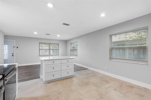 kitchen with white cabinetry, stainless steel electric range, and a kitchen island