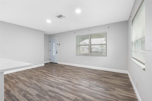 empty room featuring plenty of natural light and dark hardwood / wood-style flooring