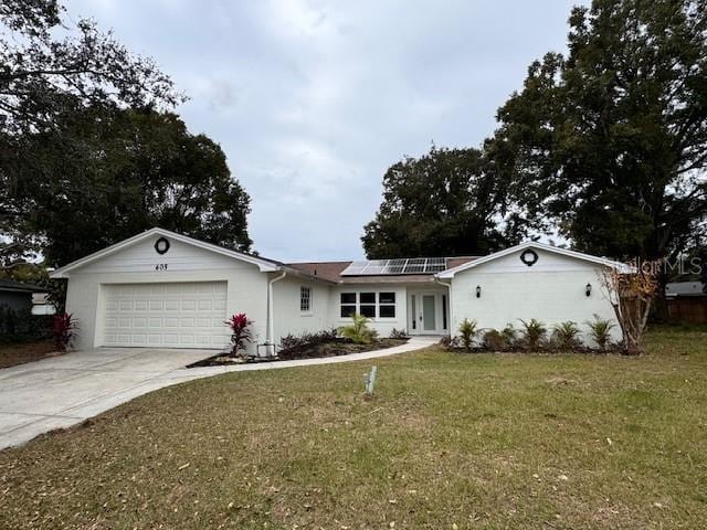 ranch-style house featuring a garage, solar panels, and a front lawn