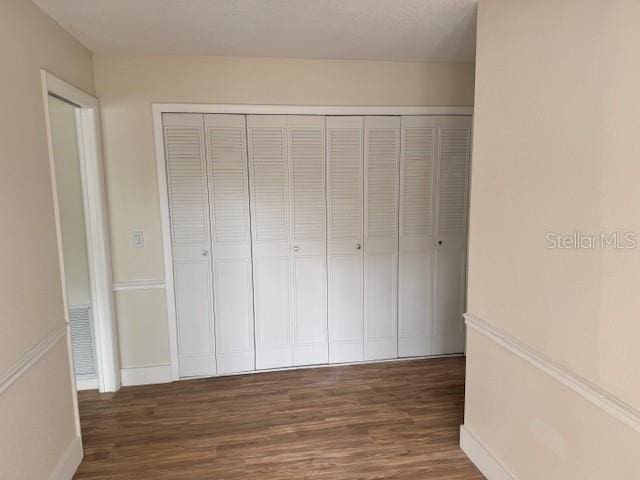 unfurnished bedroom with dark hardwood / wood-style floors and a closet