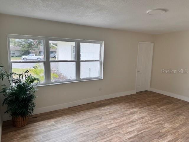 empty room with hardwood / wood-style floors and a textured ceiling