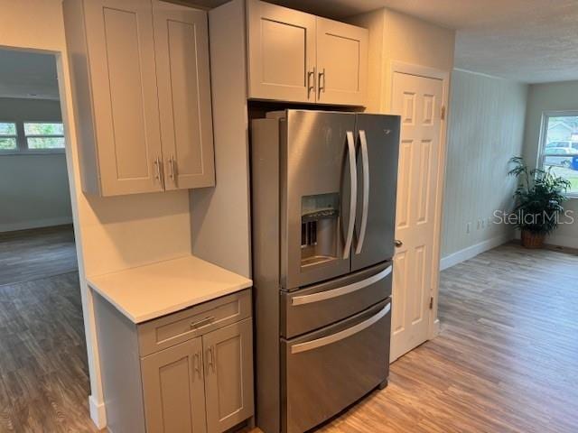 kitchen with gray cabinets, stainless steel refrigerator with ice dispenser, and light wood-type flooring