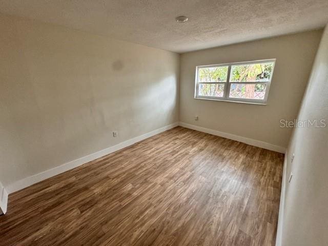 unfurnished room with hardwood / wood-style floors and a textured ceiling