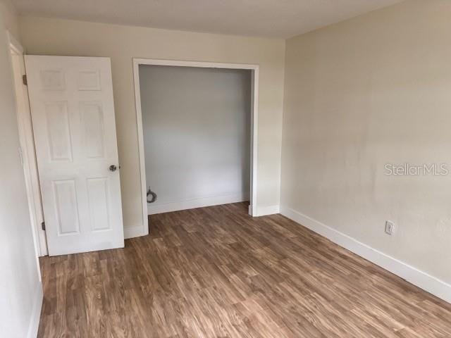 unfurnished bedroom featuring a closet and dark wood-type flooring