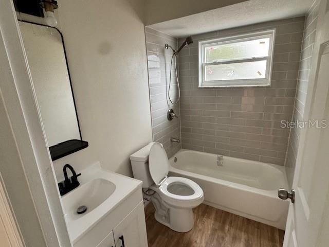 full bathroom featuring wood-type flooring, toilet, tiled shower / bath combo, and vanity