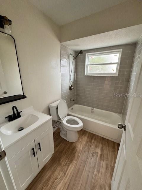 full bathroom with vanity, toilet, hardwood / wood-style floors, and tiled shower / bath combo