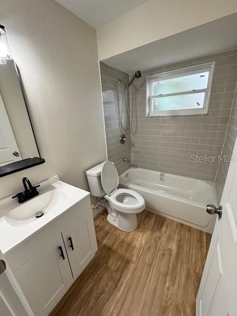 full bathroom with vanity, toilet, tiled shower / bath, and wood-type flooring