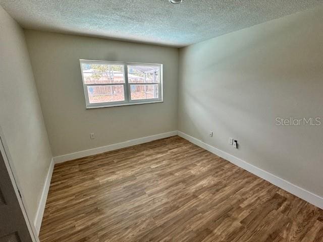 unfurnished room featuring hardwood / wood-style flooring and a textured ceiling