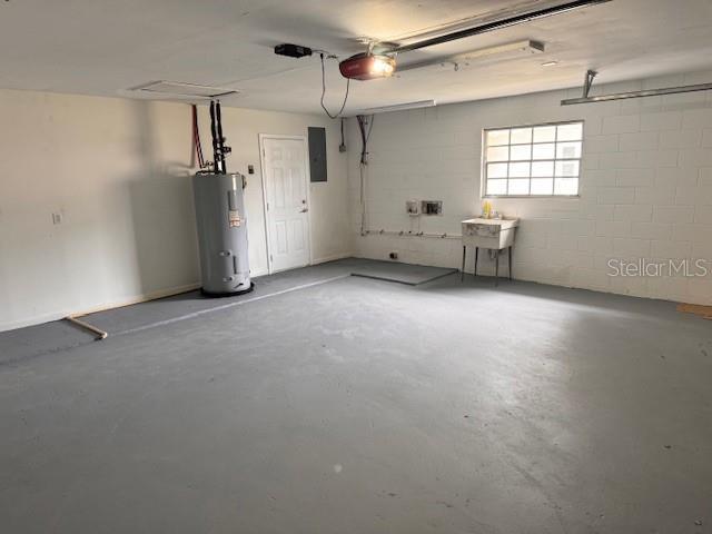 garage featuring a garage door opener, sink, and water heater