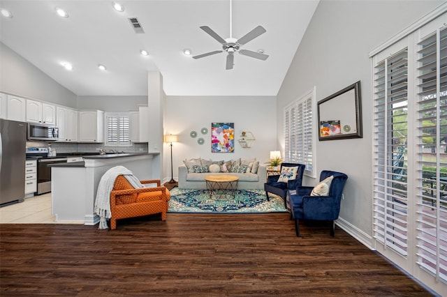 living room featuring high vaulted ceiling, ceiling fan, and light wood-type flooring