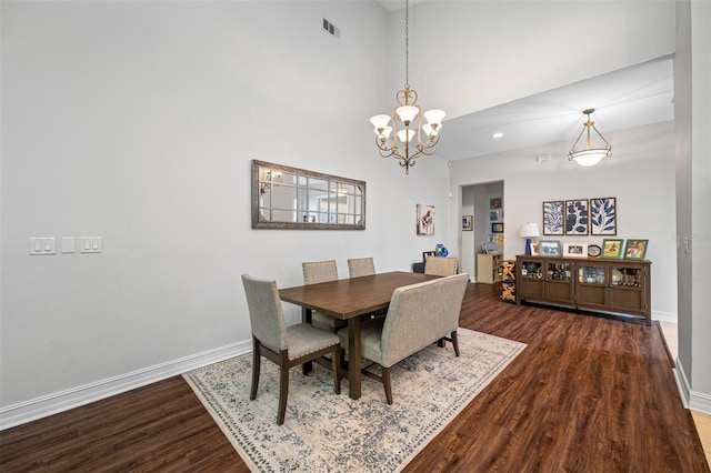 dining area featuring a high ceiling, wood-type flooring, and a notable chandelier