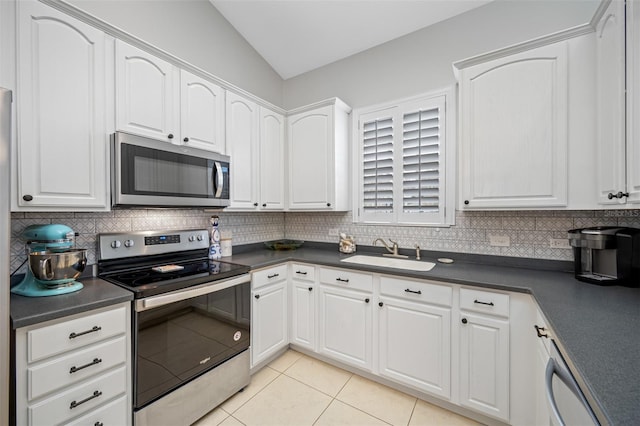 kitchen featuring sink, white cabinetry, appliances with stainless steel finishes, and vaulted ceiling