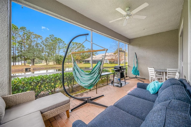 sunroom / solarium featuring a water view and ceiling fan