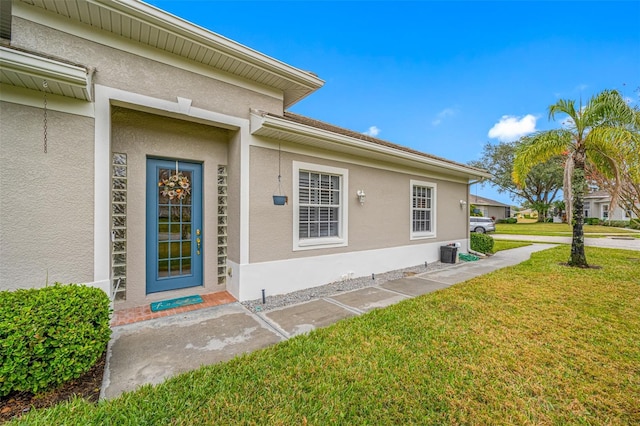 doorway to property with central AC unit and a yard