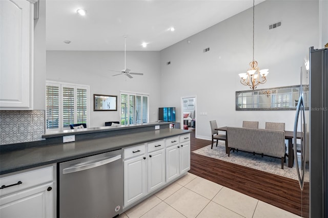 kitchen featuring white cabinetry, appliances with stainless steel finishes, decorative backsplash, and high vaulted ceiling