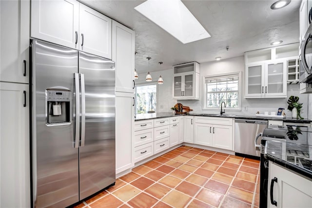 kitchen featuring white cabinetry, appliances with stainless steel finishes, a healthy amount of sunlight, and a skylight