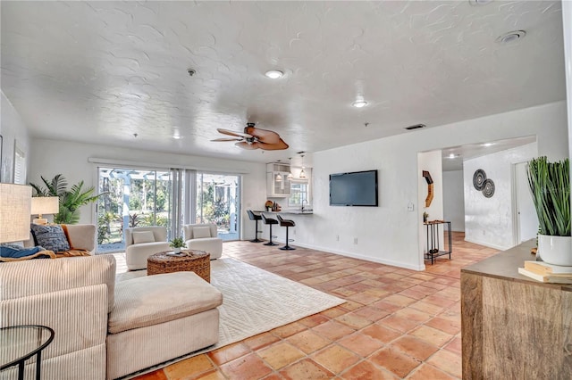 living room with ceiling fan and a textured ceiling