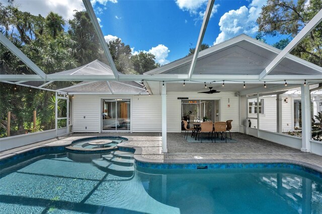 view of swimming pool with an in ground hot tub, glass enclosure, ceiling fan, and a patio area