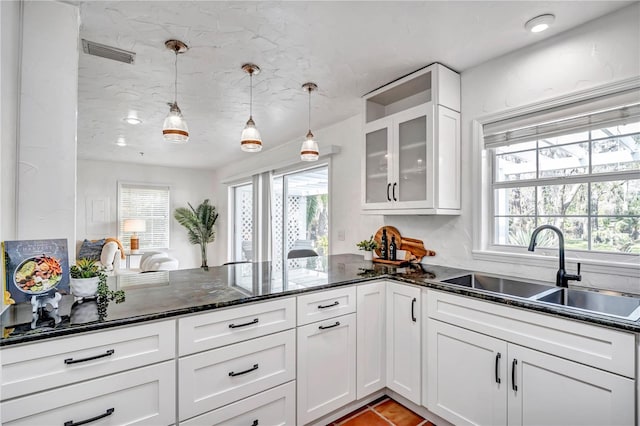 kitchen with plenty of natural light, sink, white cabinets, and decorative light fixtures