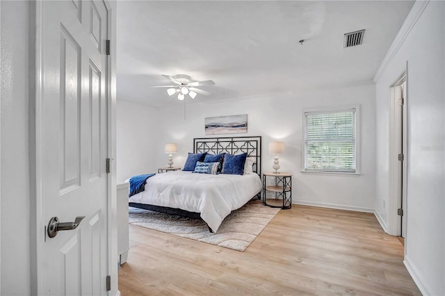 bedroom with ornamental molding, ceiling fan, and light hardwood / wood-style flooring