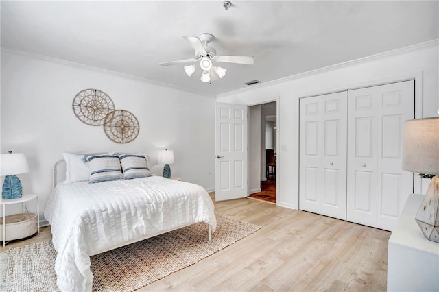 bedroom with crown molding, light hardwood / wood-style flooring, a closet, and ceiling fan