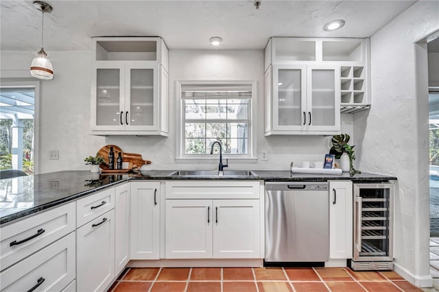 kitchen featuring dishwasher, a sink, white cabinets, beverage cooler, and dark stone counters