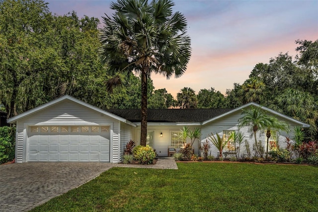single story home with an attached garage, a yard, and driveway