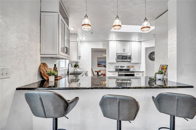 11624 Monette Rd, Riverview, FL 33569 - kitchen featuring appliances with stainless steel finishes, a peninsula, a sink, dark stone countertops, and pendant lighting