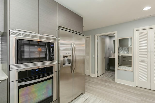 kitchen with built in appliances, light wood-type flooring, and tasteful backsplash