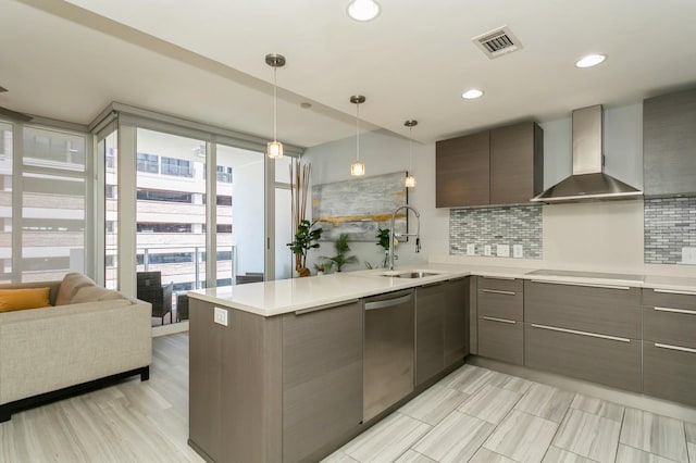 kitchen featuring a wall of windows, decorative backsplash, stainless steel dishwasher, sink, and wall chimney exhaust hood