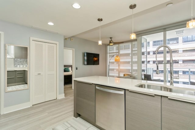 kitchen featuring sink, hanging light fixtures, light hardwood / wood-style flooring, and stainless steel dishwasher