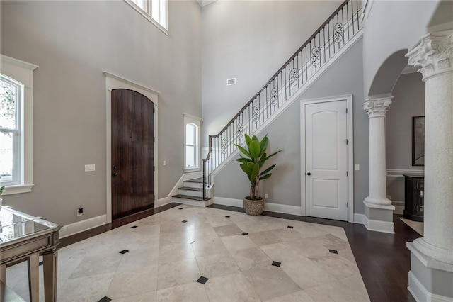 foyer featuring a wealth of natural light, a high ceiling, and ornate columns