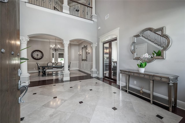 foyer featuring decorative columns, a high ceiling, ornamental molding, and french doors