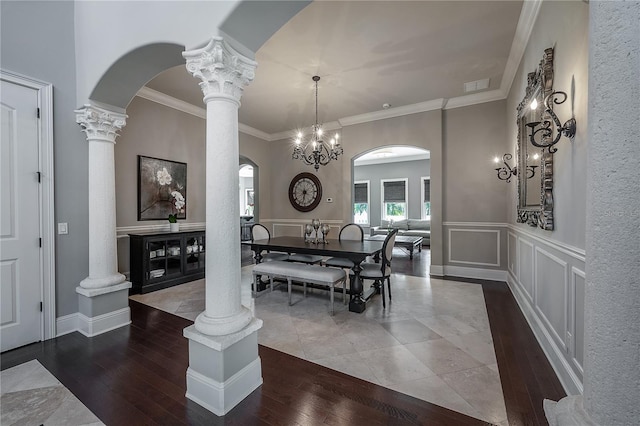 dining area with crown molding, decorative columns, and hardwood / wood-style flooring